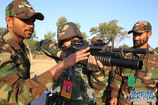资料图：2011年11月的中巴联合演习前，巴基斯坦士兵邀请中国参训士兵体验巴方装备的武器。