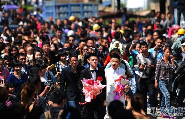 2012年10月2日，福建省最小的县城，宁德柘荣发生一件轰动全城的事情，一对男性同志在这个小县城里举行婚礼。当5辆电摩组成的迎亲队伍驶入十字街头时，全城沸腾。图为两人走在迎亲的队伍上，路上围观了近千人。