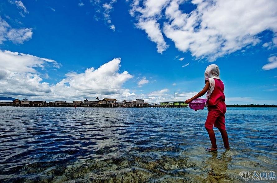 印尼苏拉威西岛，一名巴瑶族女孩趟着海水离开村子，采集海参和贝类。